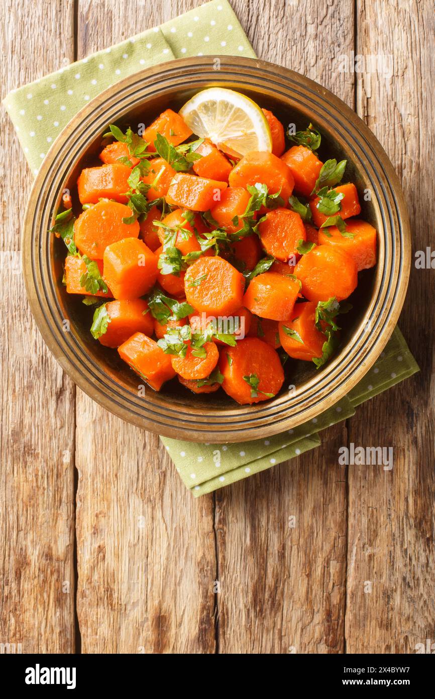 Salade traditionnelle marocaine de carottes avec coriandre, épices chaudes, vinaigrette légère de jus de citron et d'huile d'olive en gros plan sur l'assiette sur la table. Vertical Banque D'Images