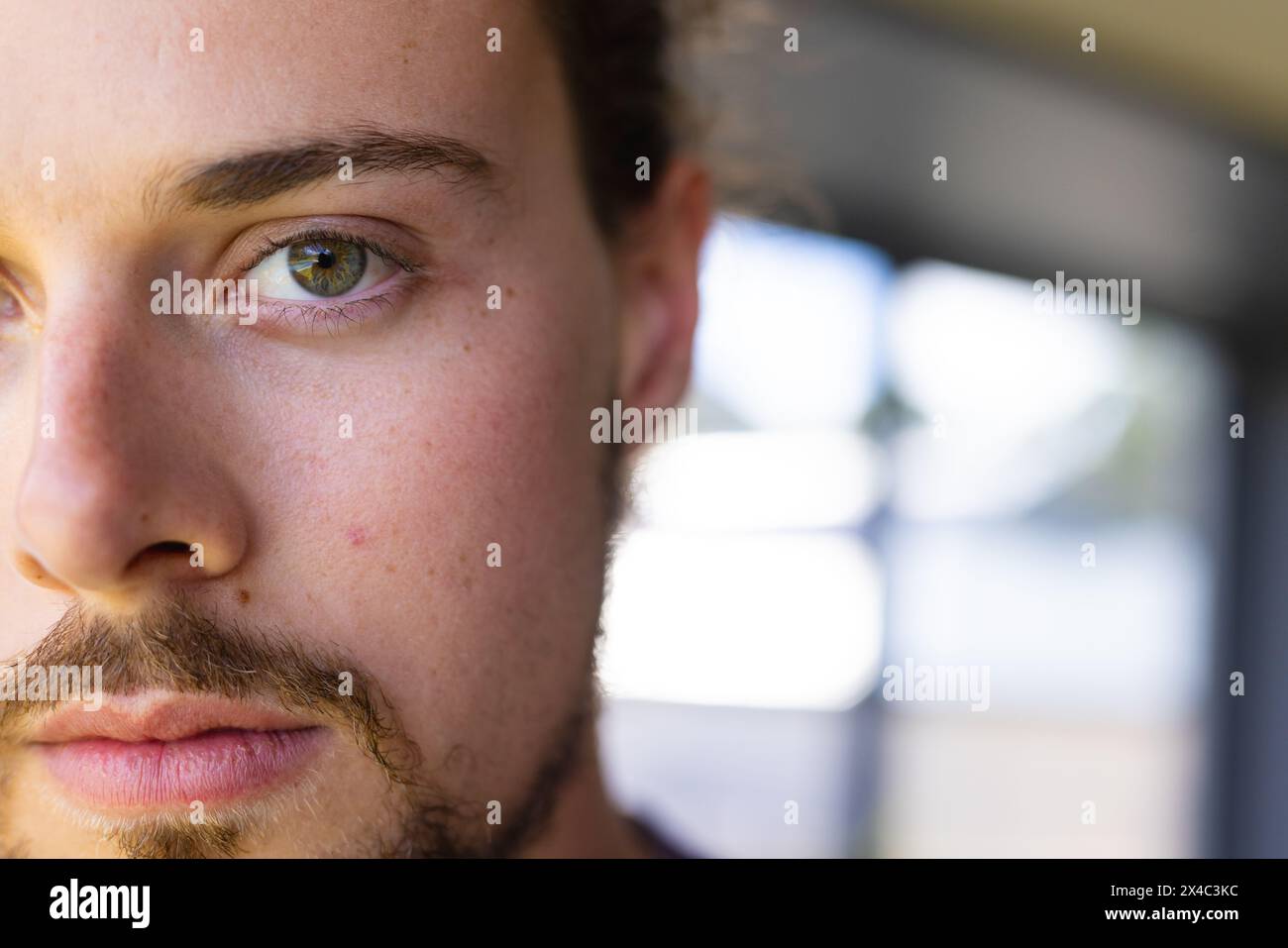 Jeune homme caucasien avec un regard sérieux debout à la maison, espace de copie. Barbe de 3 jours légère, yeux verts et cheveux bruns courts, portant un shir bleu décontracté Banque D'Images Jeune homme caucasien avec un regard sérieux debout à la maison, espace de copie. Barbe de 3 jours légère, yeux verts et cheveux bruns courts, portant un shir bleu décontracté Banque D'Images