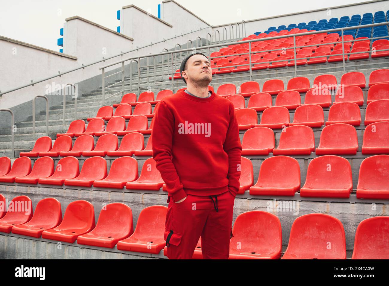 Homme debout devant le stade vide. Un homme se tient seul devant un stade vacant, mettant en valeur l'atmosphère désolée dans le vaste espace vide Banque D'Images