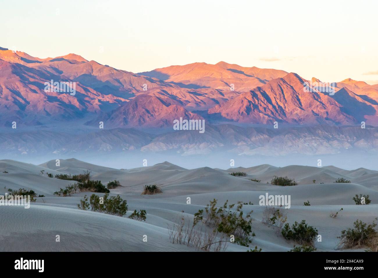 États-Unis, Californie, parc national de la Vallée de la mort. Montagnes et sable soufflé dans Mesquite Dunes au coucher du soleil. Banque D'Images