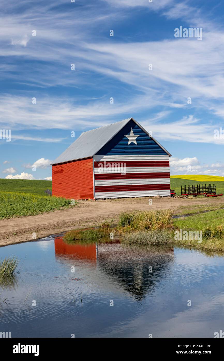 États-Unis, Idaho, Genesee. Grange peinte en rouge, blanc et bleu et reflet dans un petit étang Banque D'Images