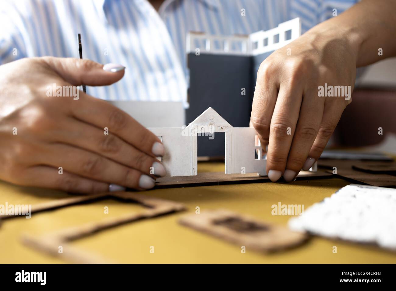 Une fille assemble un modèle d'un bâtiment à partir de carton épais. Banque D'Images