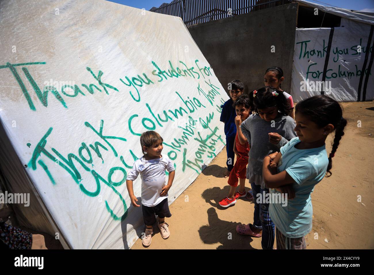 Rafah, Gaza. 02 mai 2024. Des enfants palestiniens déplacés se tiennent devant une tente, ornée de slogans exprimant leur gratitude aux étudiants américains pour leur soutien aux Palestiniens et leur condamnation de la guerre israélienne contre Gaza, à Rafah, dans le sud de Gaza, jeudi 2 mai 2024. Photo de Ismael Mohamad/UPI crédit : UPI/Alamy Live News Banque D'Images