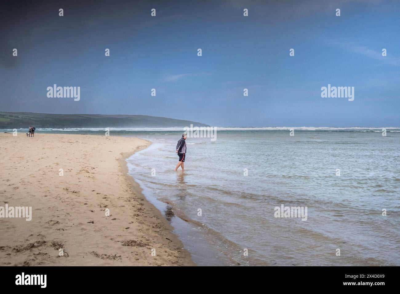 Un visiteur pagayant dans la mer sur Crantock Beach à Newquay en Cornouailles au Royaume-Uni. Banque D'Images