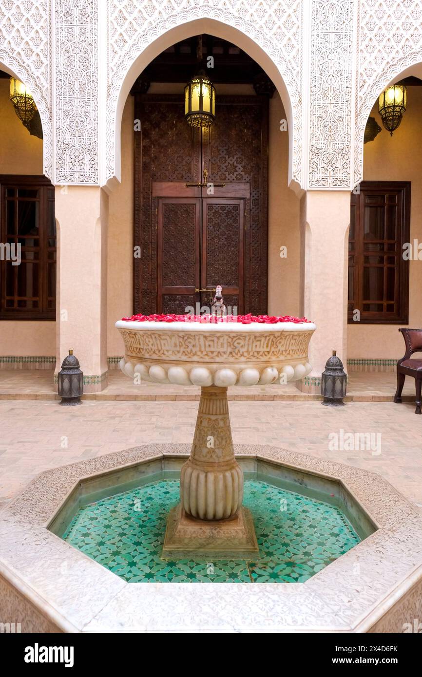 Marrakech, Maroc. Fontaine remplie de roses dans la cour du riad Banque D'Images