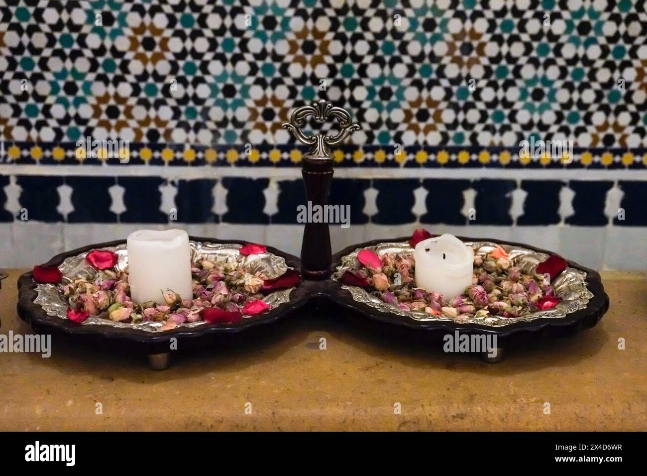 Fès, Maroc. Intérieur d'un hammam féminin. Plateau de roses séchées et bougies près de la salle de bain. Banque D'Images