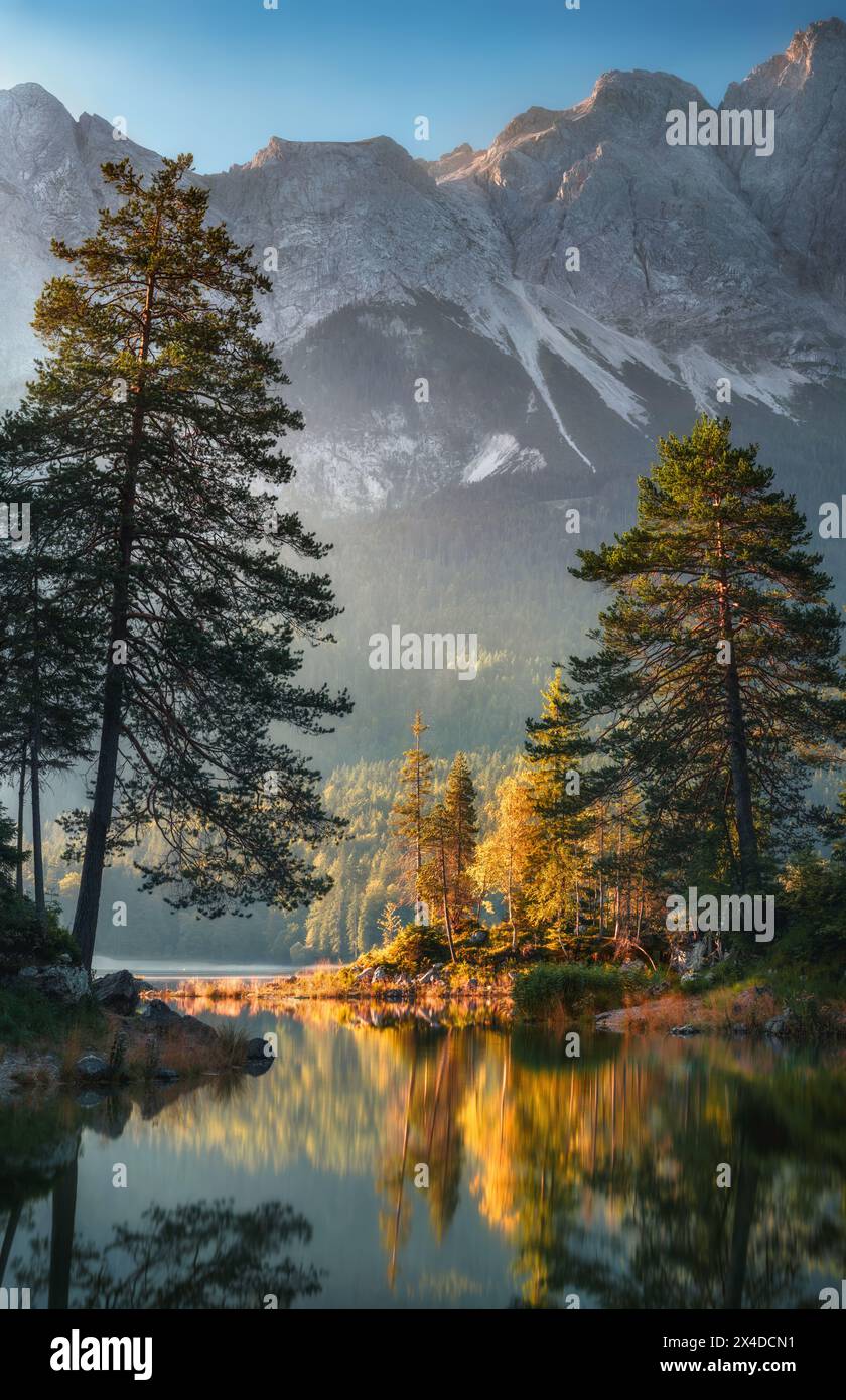 Paysage idyllique au lac allemand Eibsee dans les Alpes, avec des montagnes et des arbres reflétés dans l'eau claire et belle lumière Banque D'Images