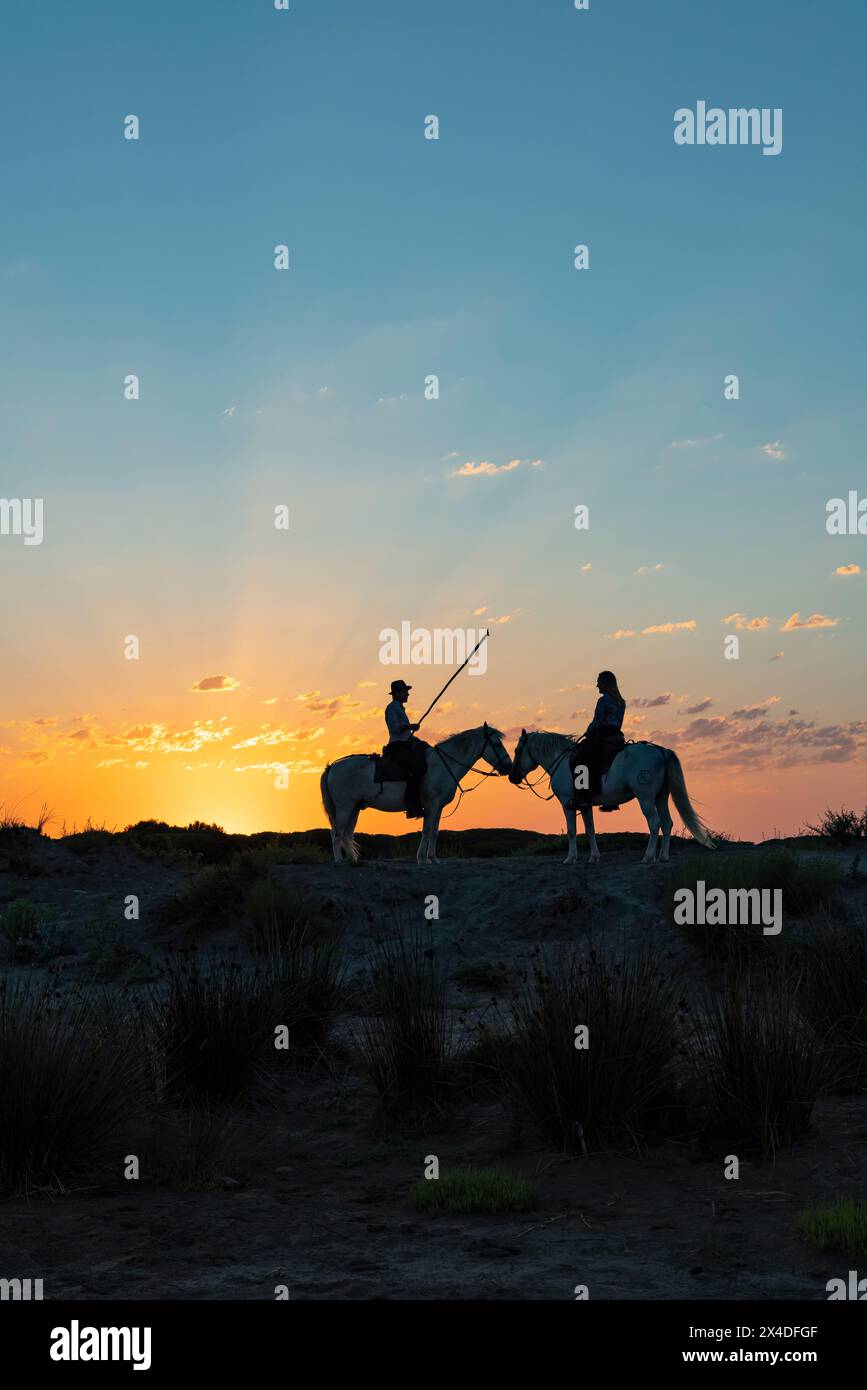 Saintes-Maries-de-la-mer, Bouches-du-Rhône, Provence-Alpes-Côte d'Azur, France. Un homme et une femme à cheval au lever du soleil. (Usage éditorial uniquement) Banque D'Images