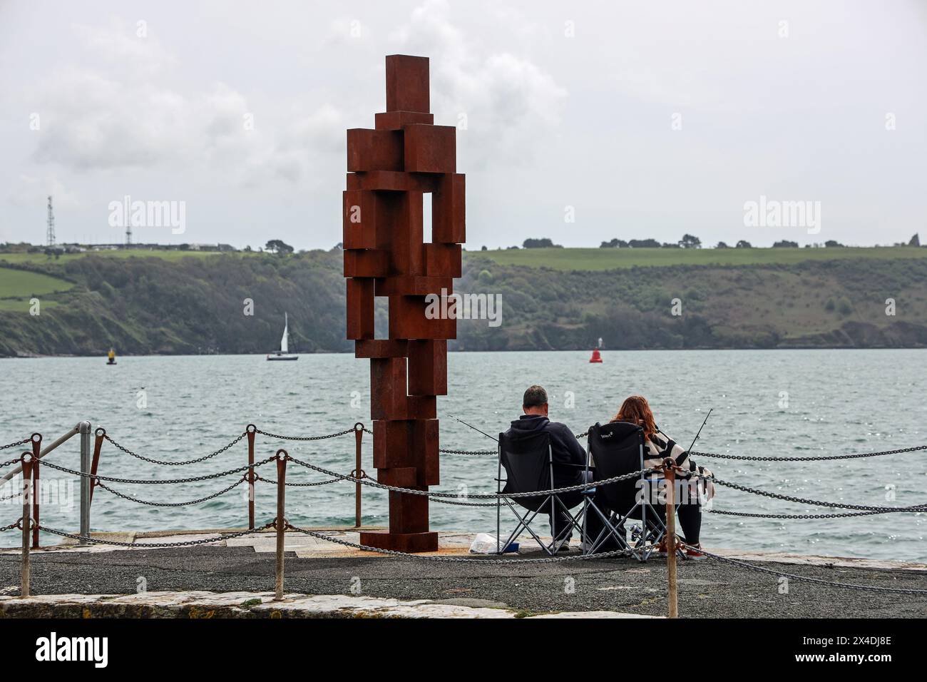 Ami du pêcheur, la sculpture look II tient compagnie à un couple de pêcheurs sur West Hoe Pier Plymouth. Sculpture de 12 pieds « look II » de Sir Anthony Gormley sur West H. Banque D'Images