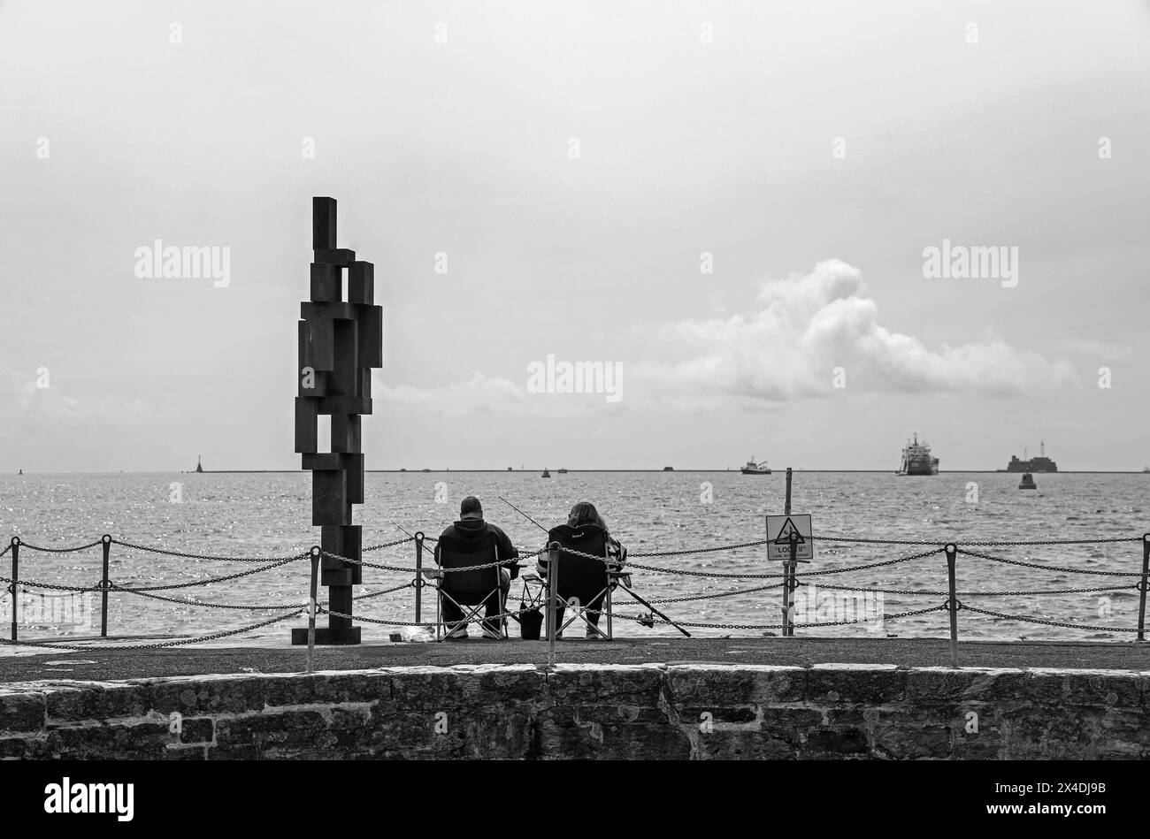 Ami du pêcheur, la sculpture look II tient compagnie à un couple de pêcheurs sur West Hoe Pier Plymouth. Sculpture de 12 pieds « look II » de Sir Anthony Gormley sur West H. Banque D'Images