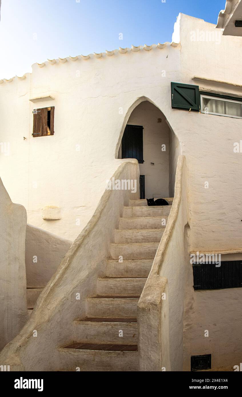 Un ejemplo de una casa del pintoresco y encantador pueblo de Binibeca con un gato negro sentado en la escalera. Minorque, España Banque D'Images
