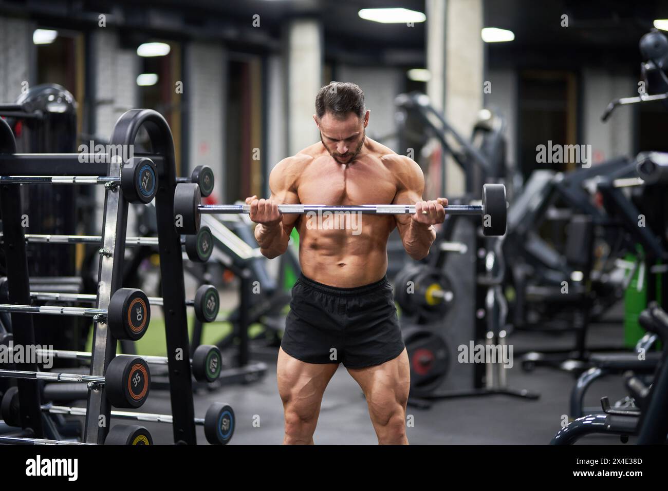 Athlète masculin fort tenant barre, haltérophilie dans le gymnase. Vue avant de l'homme caucasien musclé soulevant l'équipement de barre, l'exercice, contre le blurre Banque D'Images Athlète masculin fort tenant barre, haltérophilie dans le gymnase. Vue avant de l'homme caucasien musclé soulevant l'équipement de barre, l'exercice, contre le blurre Banque D'Images