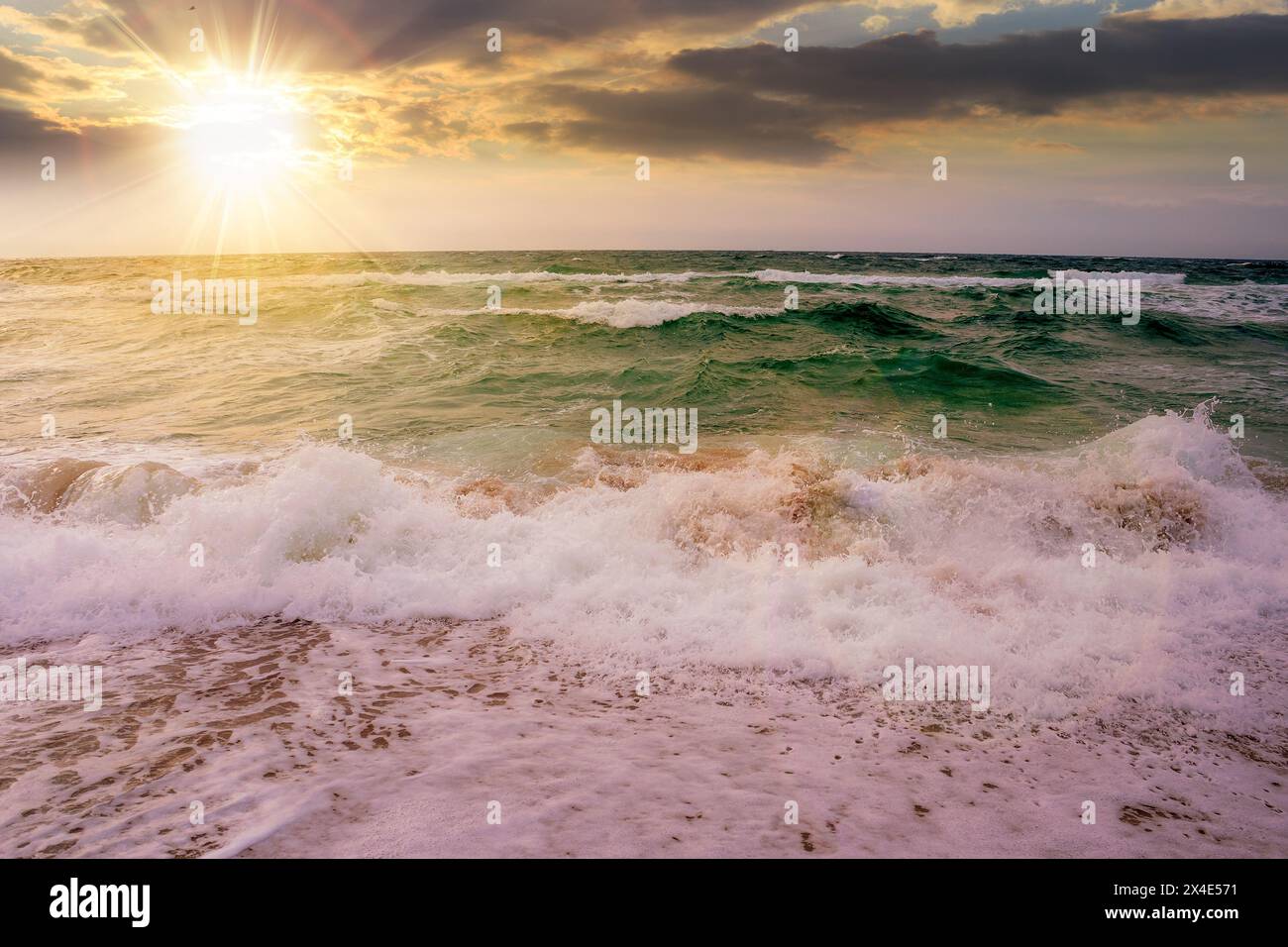 les vagues s'écrasent sur le rivage au coucher du soleil. paysage marin orageux dans la lumière du soir Banque D'Images