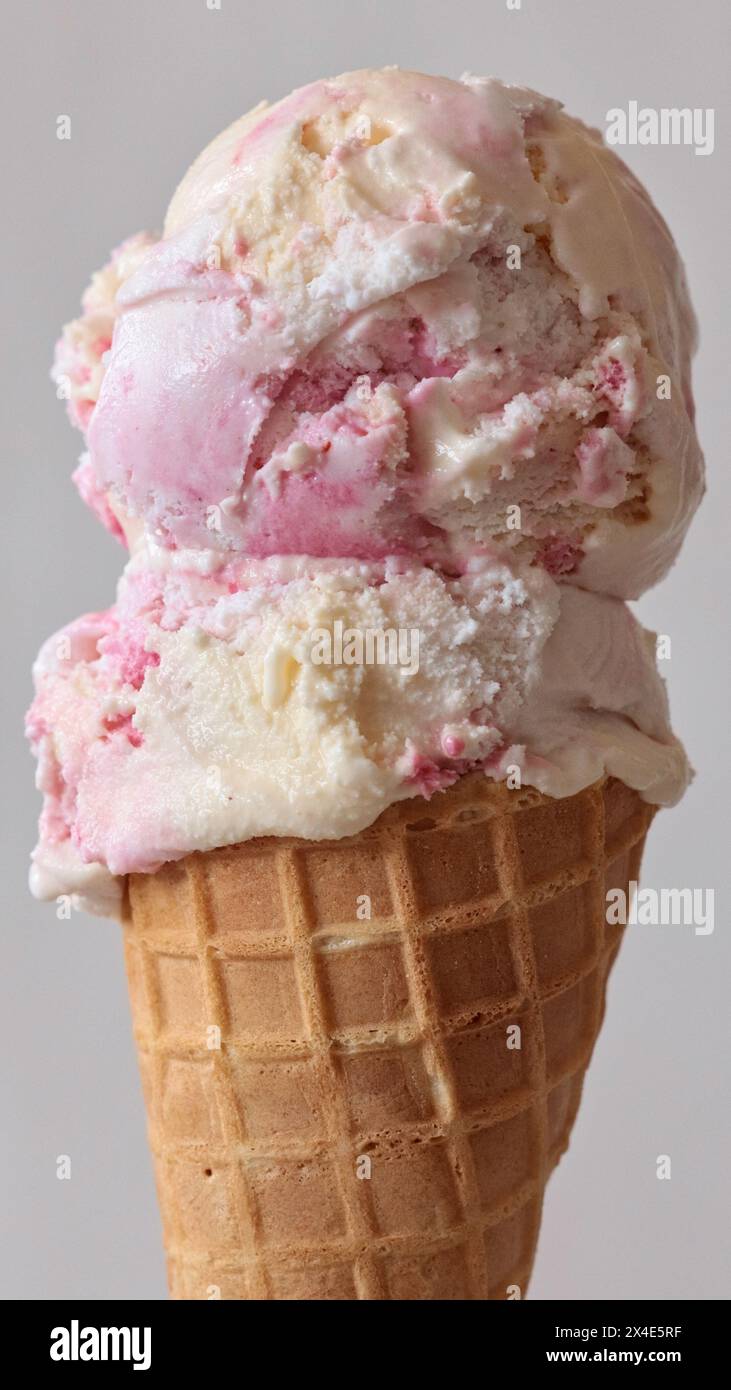 gros plan de cône de gaufre de crème glacée et cuillère à crème glacée à saveur de fraise vanille sur fond gris clair Banque D'Images