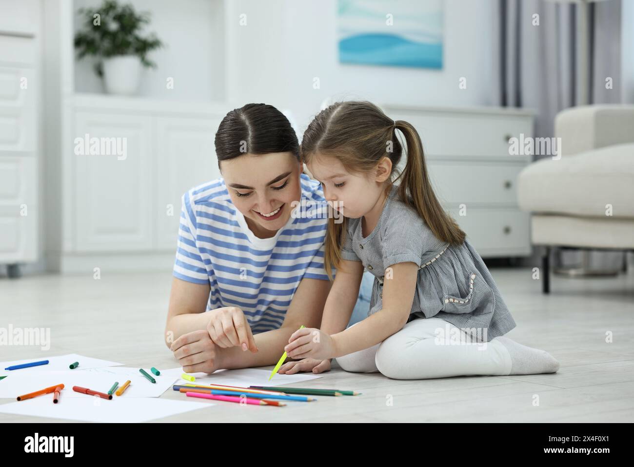 Mère et sa petite fille dessinent avec des marqueurs colorés sur le sol à la maison Banque D'Images