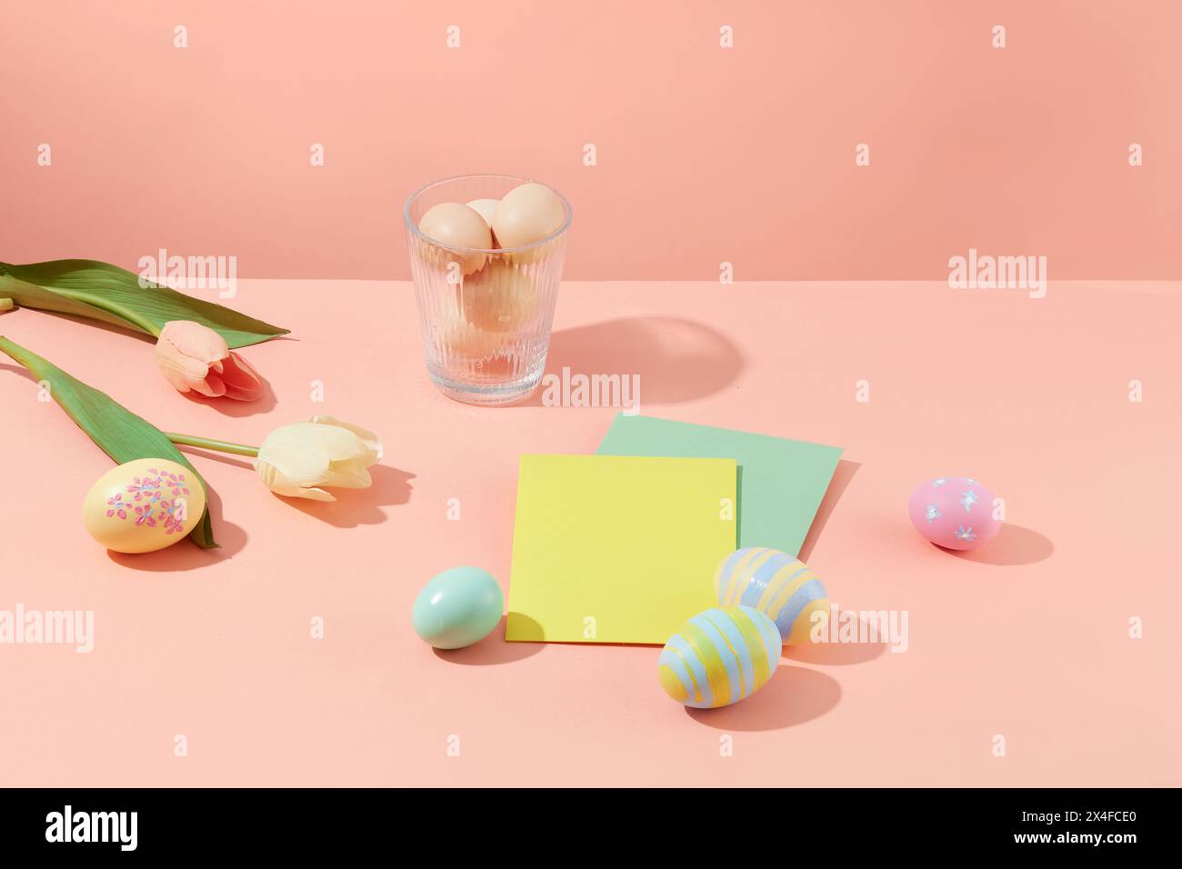 Scène d'oeufs colorés décorés de fleurs et de carte de papier sur un fond rose pastel. Faites vos propres œufs de Pâques comme cadeaux significatifs Banque D'Images