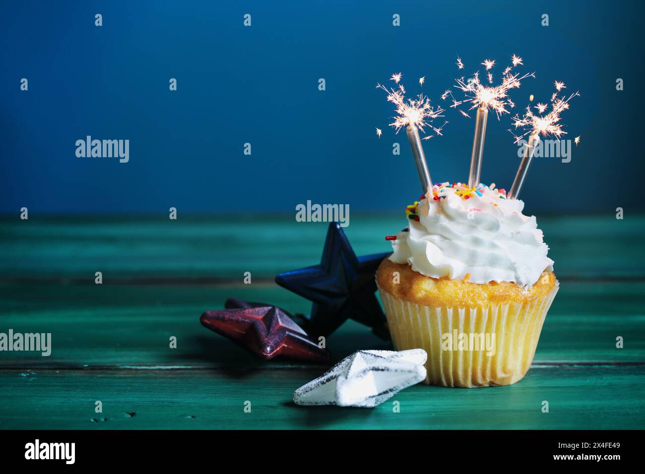 Célébration d'un cupcake à la vanille avec un glaçage à la crème au beurre décoré de saupoudres de sucre et de pétillants pour le 4 juillet. Mise au point sélective avec b flou Banque D'Images