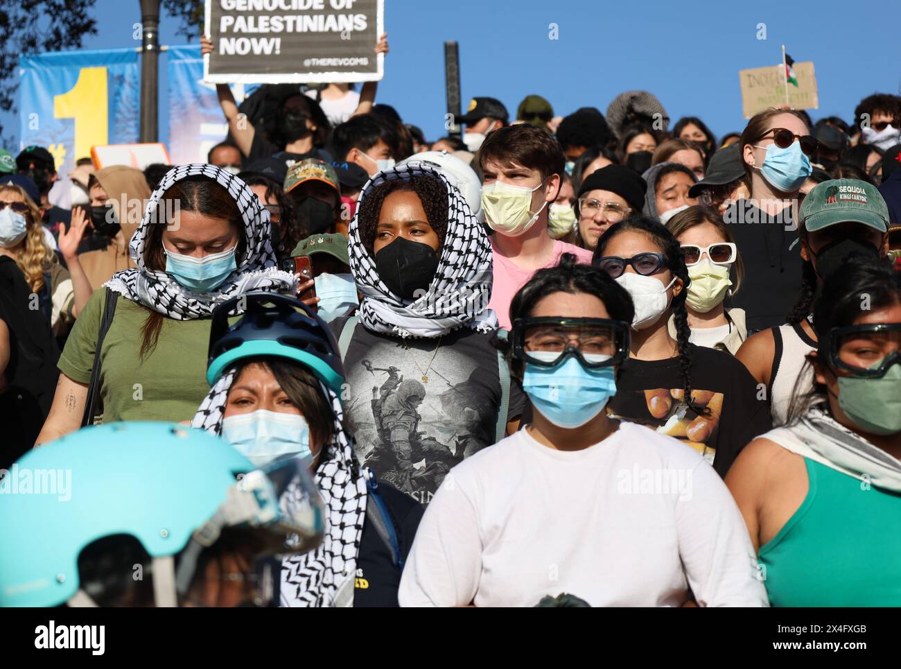 Los Angeles, Californie, États-Unis 1er mai 2024. Université de Californie, Los Angeles (UCLA) le 1er mai 2024 : des manifestants pro-Palestine/Hamas portant un foulard et un masque facial, des casques et des lunettes de protection se rassemblent près de leur campement sur le campus pour écouter des orateurs les encourageant à continuer à protester et à résister à l'arrestation. La femme au centre porte un T-SHIRT QUI porte le logo « Assassin's Creed » et une image d'un homme avec une hache tuant quelqu'un. (Crédit image : © Amy Katz/ZUMA Press Wire) USAGE ÉDITORIAL SEULEMENT! Non destiné à UN USAGE commercial ! Banque D'Images