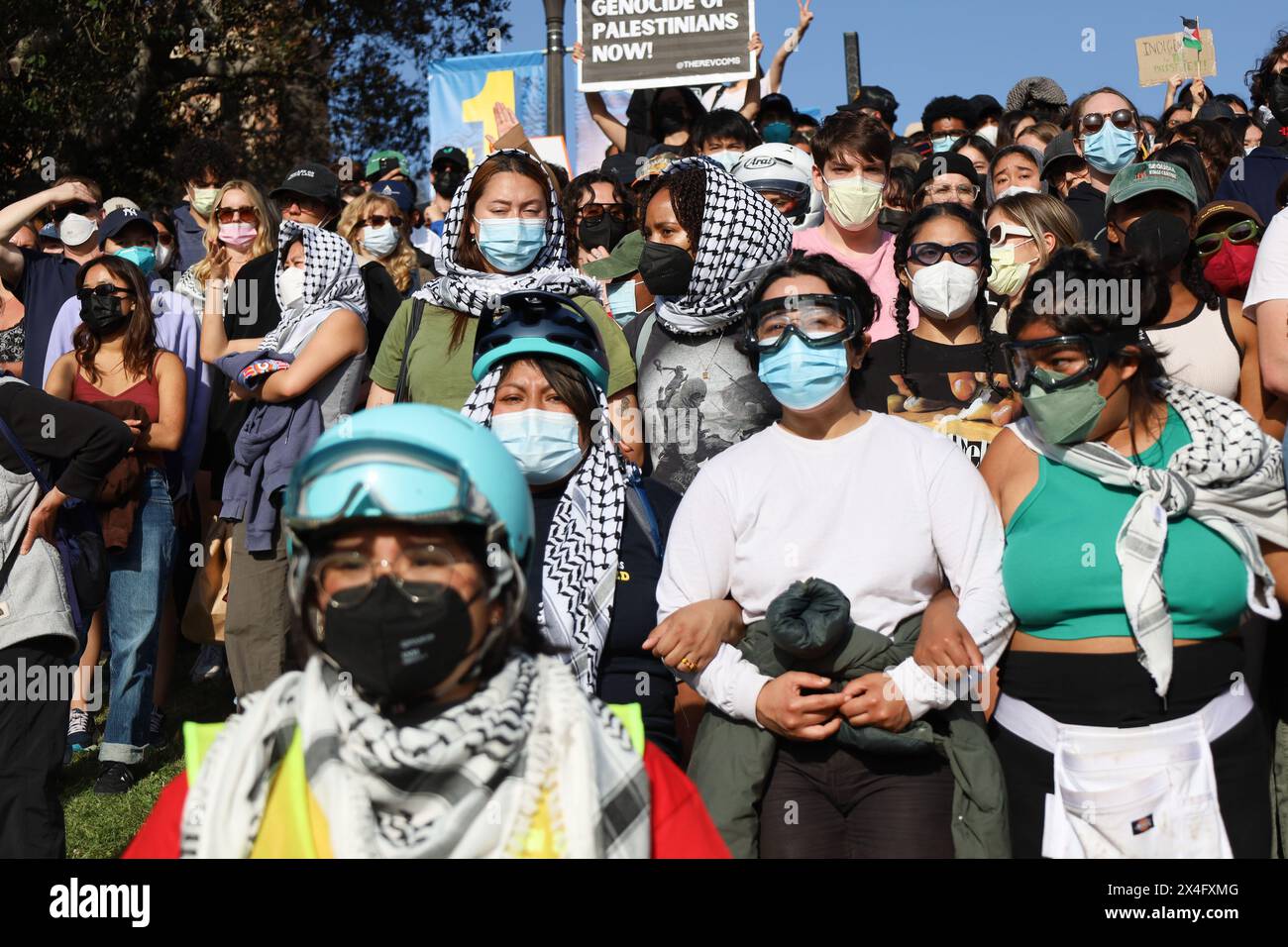 Los Angeles, Californie, États-Unis 1er mai 2024. Université de Californie, Los Angeles (UCLA) le 1er mai 2024 : des manifestants pro-Palestine/Hamas portant un foulard et un masque facial, des casques et des lunettes de protection se rassemblent près de leur campement sur le campus pour écouter des orateurs les encourageant à continuer à protester et à résister à l'arrestation. La femme au centre porte un T-SHIRT QUI porte le logo « Assassin's Creed » et une image d'un homme avec une hache tuant quelqu'un. (Crédit image : © Amy Katz/ZUMA Press Wire) USAGE ÉDITORIAL SEULEMENT! Non destiné à UN USAGE commercial ! Banque D'Images