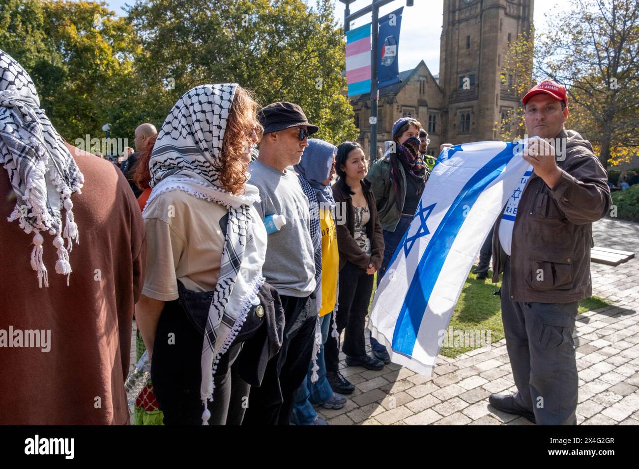 Un contre-manifestant agite un drapeau israélien sur les manifestants lors d'une manifestation pro-palestinienne sur le campus de l'Université de Melbourne. Le pro-israélien porte une casquette Make America Great Again. Melbourne, Victoria, Australie. Banque D'Images