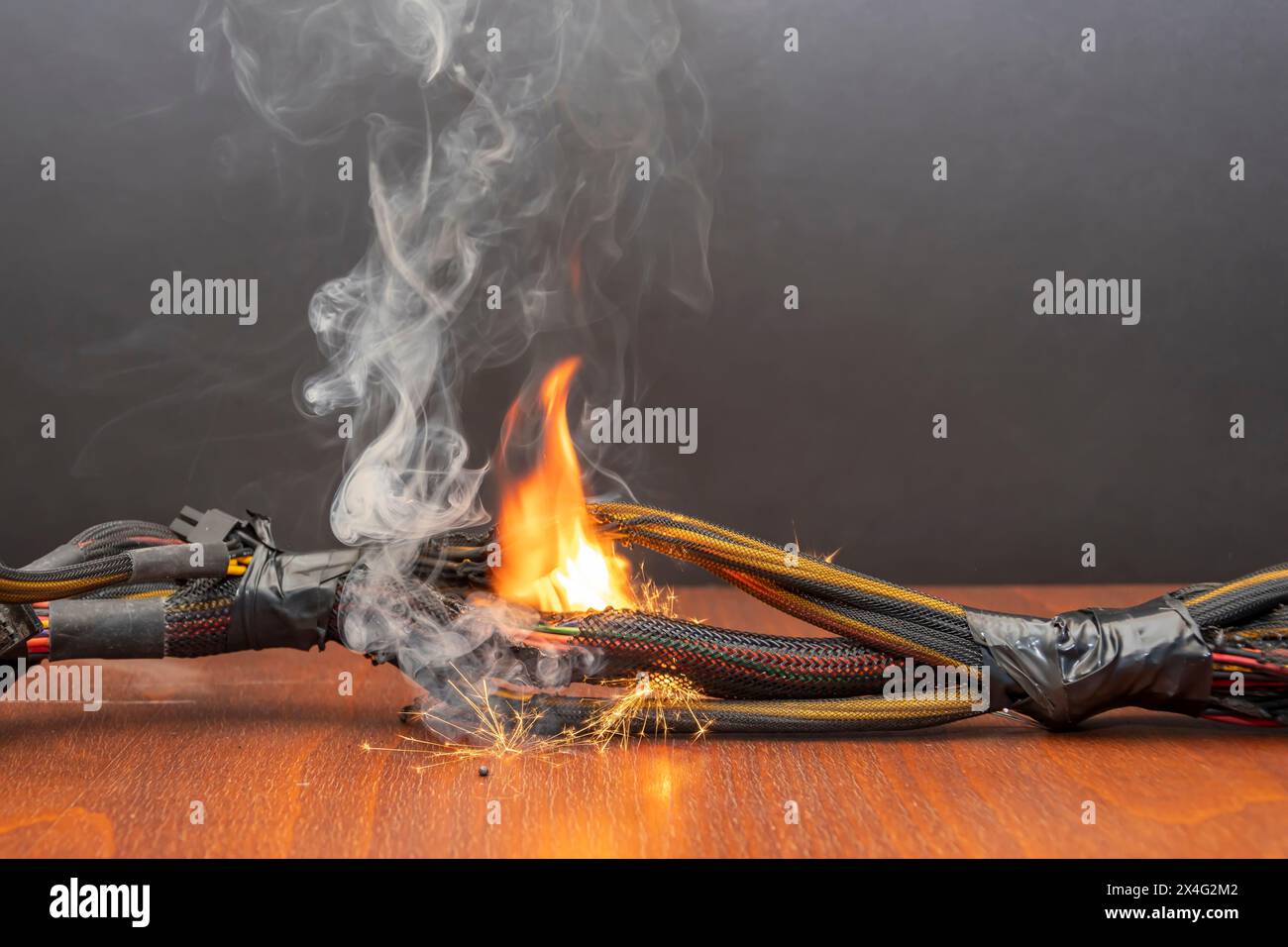 Le câblage électrique et les fils sont éclairés sur un fond sombre. Un court-circuit dans les fils torsadés du calculateur. Flammes, étincelles et fumée. Banque D'Images