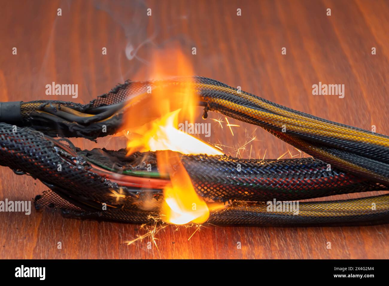 Le câblage électrique et les fils sont éclairés sur un fond sombre. Un court-circuit dans les fils torsadés du calculateur. Flammes, étincelles et fumée. Banque D'Images