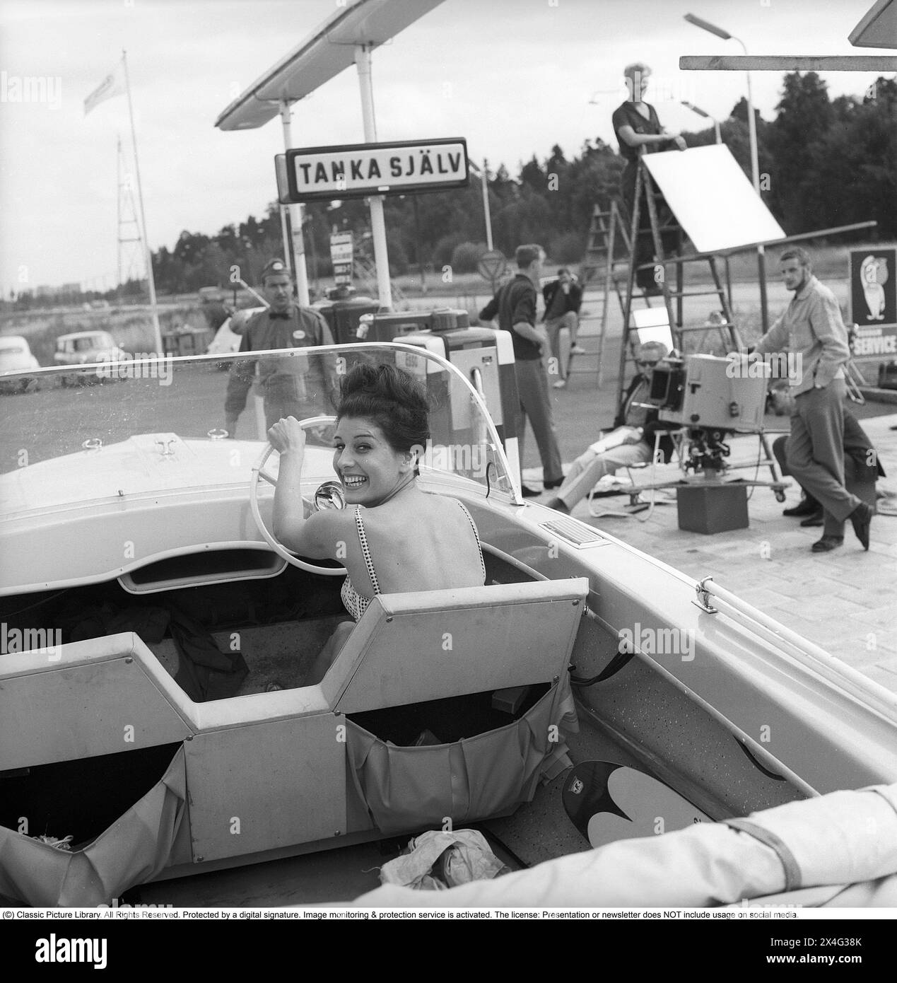 Station-service Esso en 1963. La société Svenska Esso était une marque suédoise entre les années 1939 et 1987, lorsque les stations ont changé leur nom pour le nom du nouveau propriétaire, Statoil. À la station-service, une publicité est filmée où un bateau à moteur se tient près des pompes à essence avec une jeune femme vue au volant. Kristoffersson réf. DC135-12 Banque D'Images