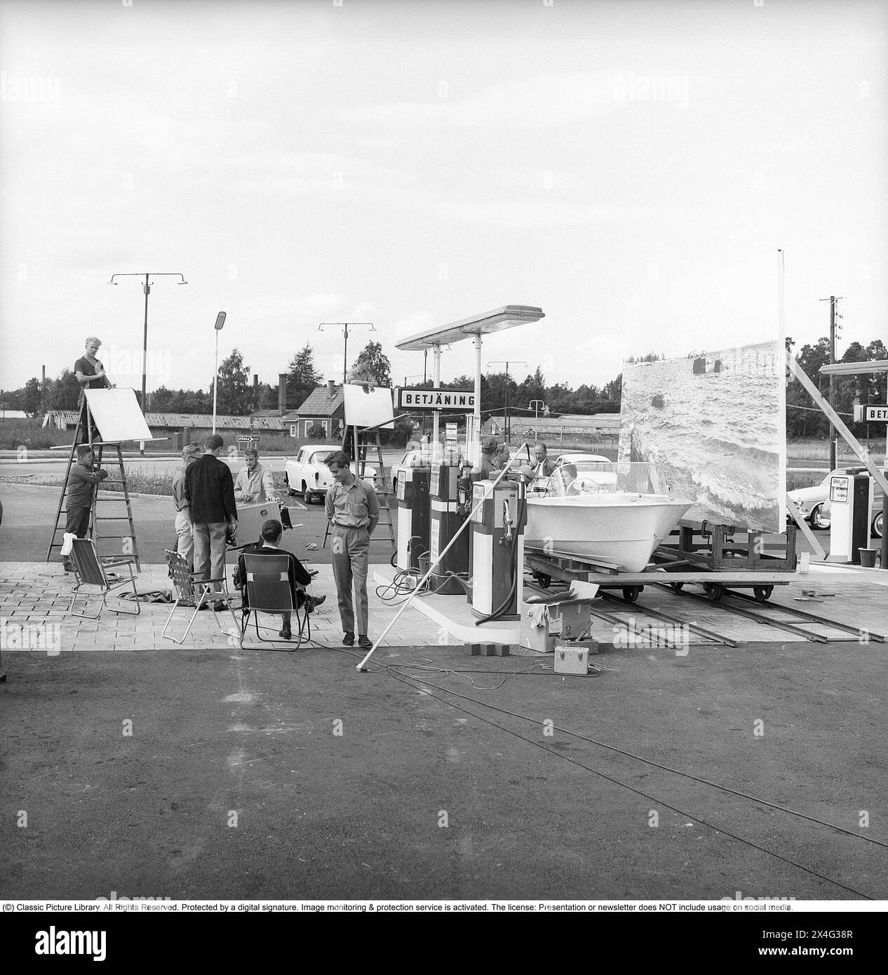 Station-service Esso en 1963. La société Svenska Esso était une marque suédoise entre les années 1939 et 1987, lorsque les stations ont changé leur nom pour le nom du nouveau propriétaire, Statoil. À la station-service, une publicité est filmée où un bateau à moteur se tient près des pompes à essence. Un arrière-plan représentant un océan est utilisé comme arrière-plan. Kristoffersson réf. DC135-7 Banque D'Images