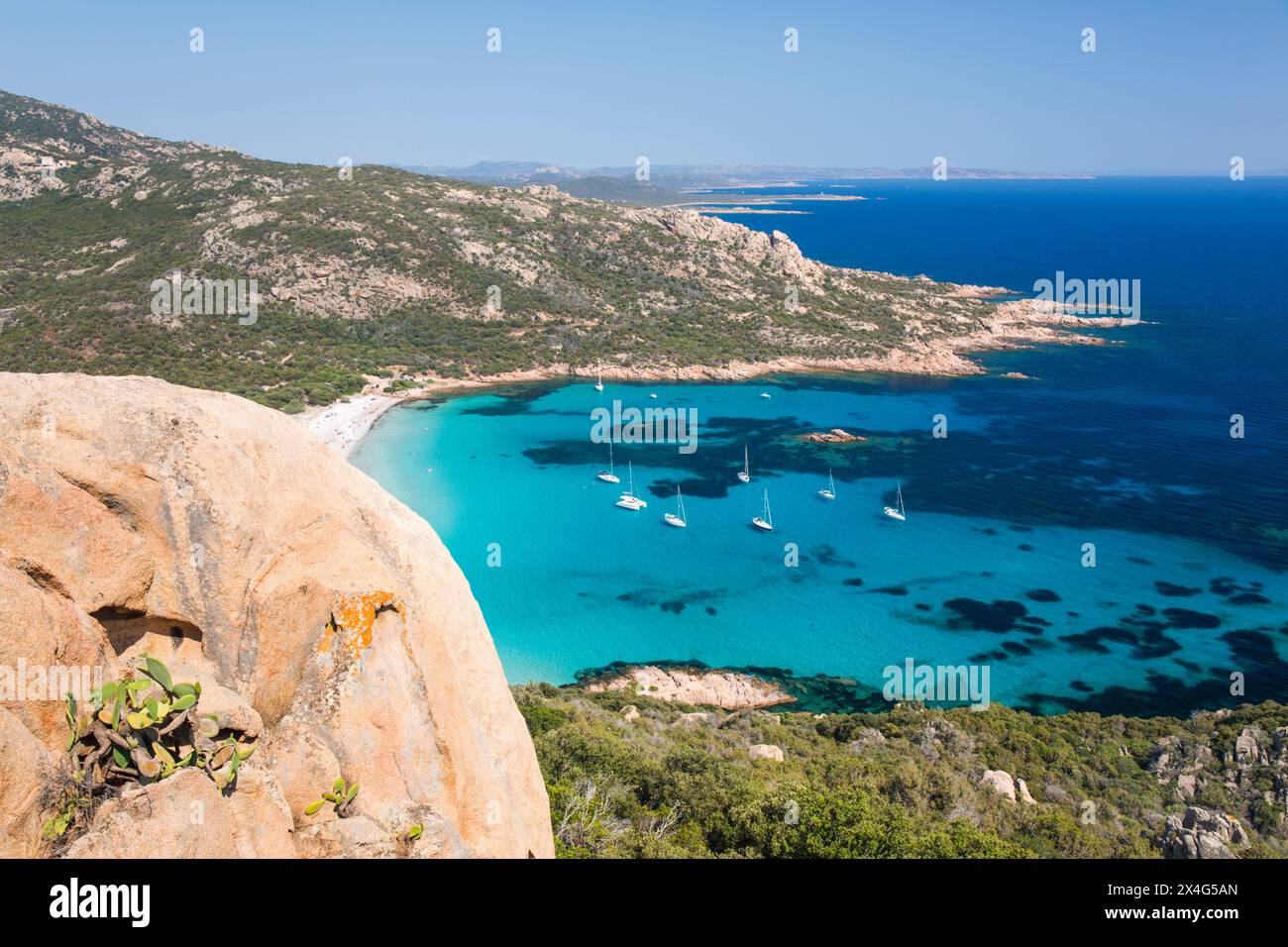 Sartène, Corse-du-Sud, Corse, France. Vue sur les eaux turquoises de la Cala di Roccapina depuis le sommet d'une colline rocheuse, yachts ancrés dans la baie. Banque D'Images