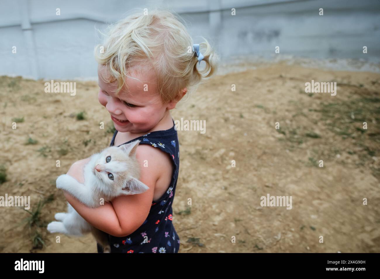 Enfant souriant tenant tendrement un chaton blanc Banque D'Images