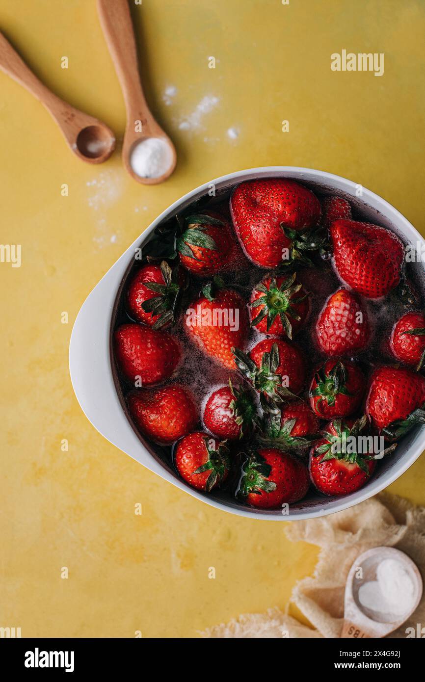 Fraises lavées dans un bol blanc avec du bicarbonate de soude et du bois Banque D'Images