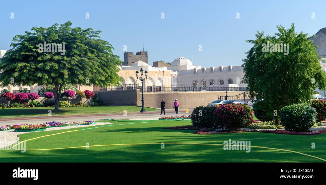 Muscat, Oman - 2 janvier 2024 : les visiteurs profitent d'une promenade sereine au milieu des jardins luxuriants de la place du Palais Al Alam sous le doux soleil. Banque D'Images