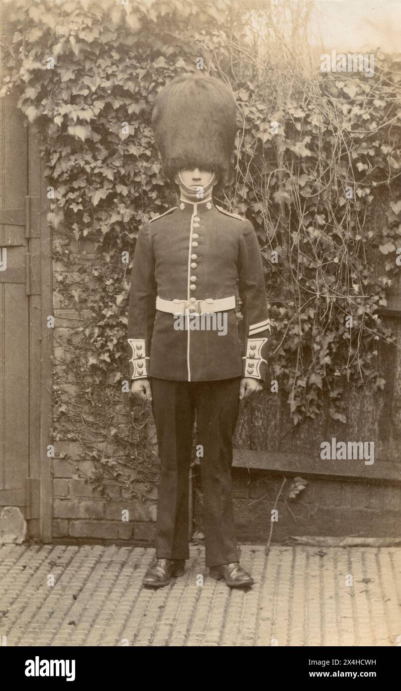 Londres circa.1910 - Un gardien des Coldstream Guards posté pour une photographie vêtu de son uniforme de cérémonie et d'une casquette en peau d'ours. Il porte deux bandes de bonne conduite sur la manche de sa tunique, indiquant qu'il a accompli 6 ans de service irréprochable. Banque D'Images