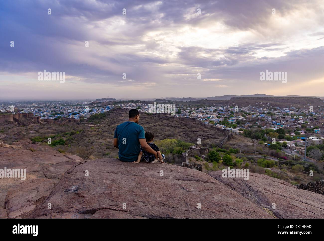 isolez père et enfant fils regardant le paysage de la ville au sommet de la montagne avec le ciel dramatique au crépuscule image est prise à mehrangarh jodhpur rajasthan inde. Banque D'Images