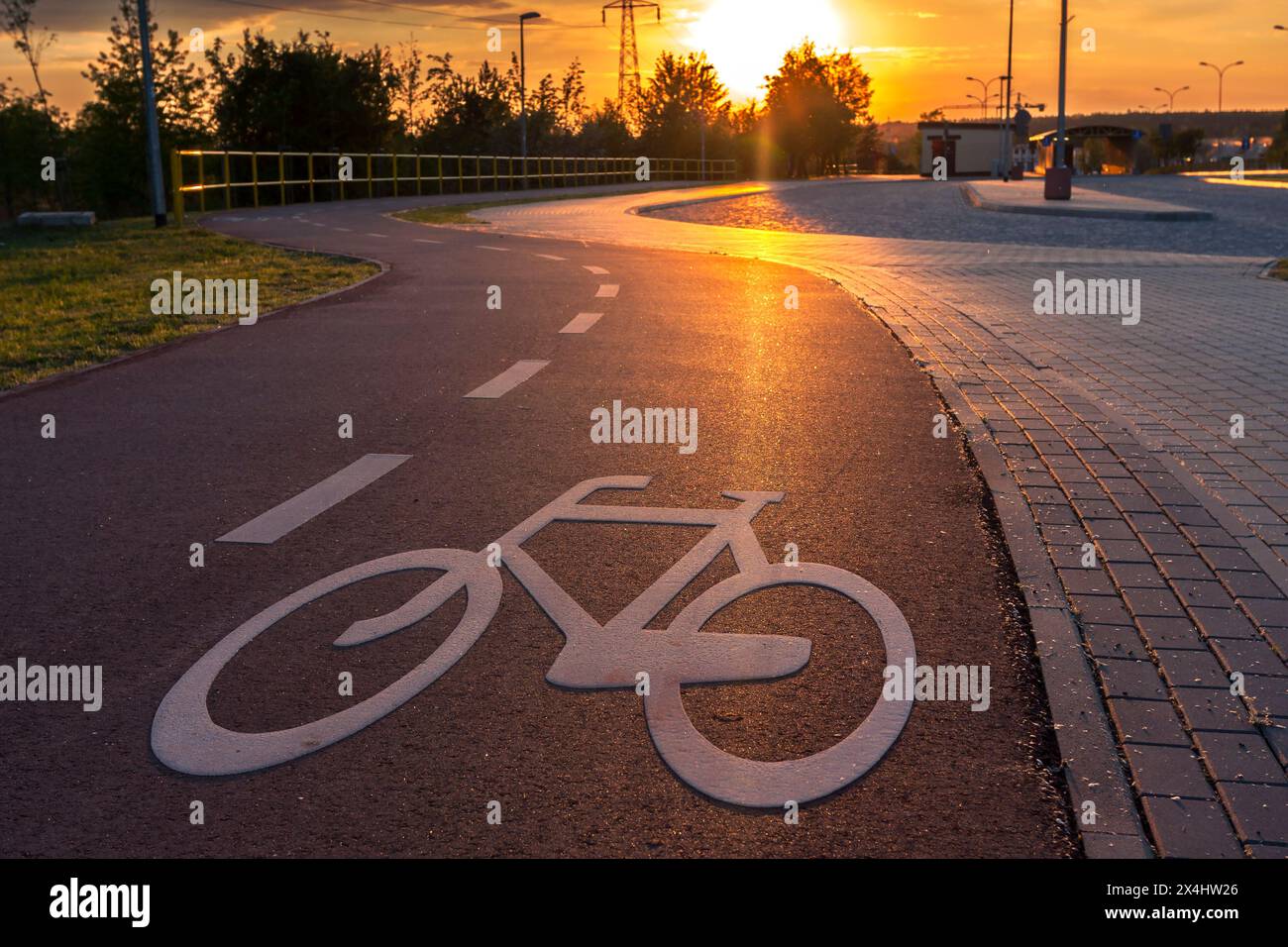 Une piste cyclable dans la ville marquée par un symbole, le soleil couchant illumine le panneau de vélo Banque D'Images