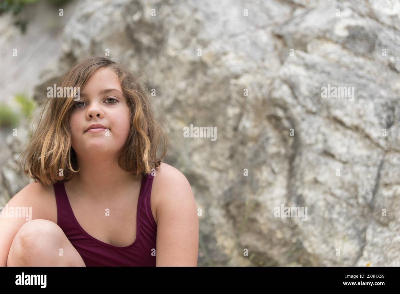 Belle fille en maillot de bain assise sur les rochers regardant la caméra Banque D'Images