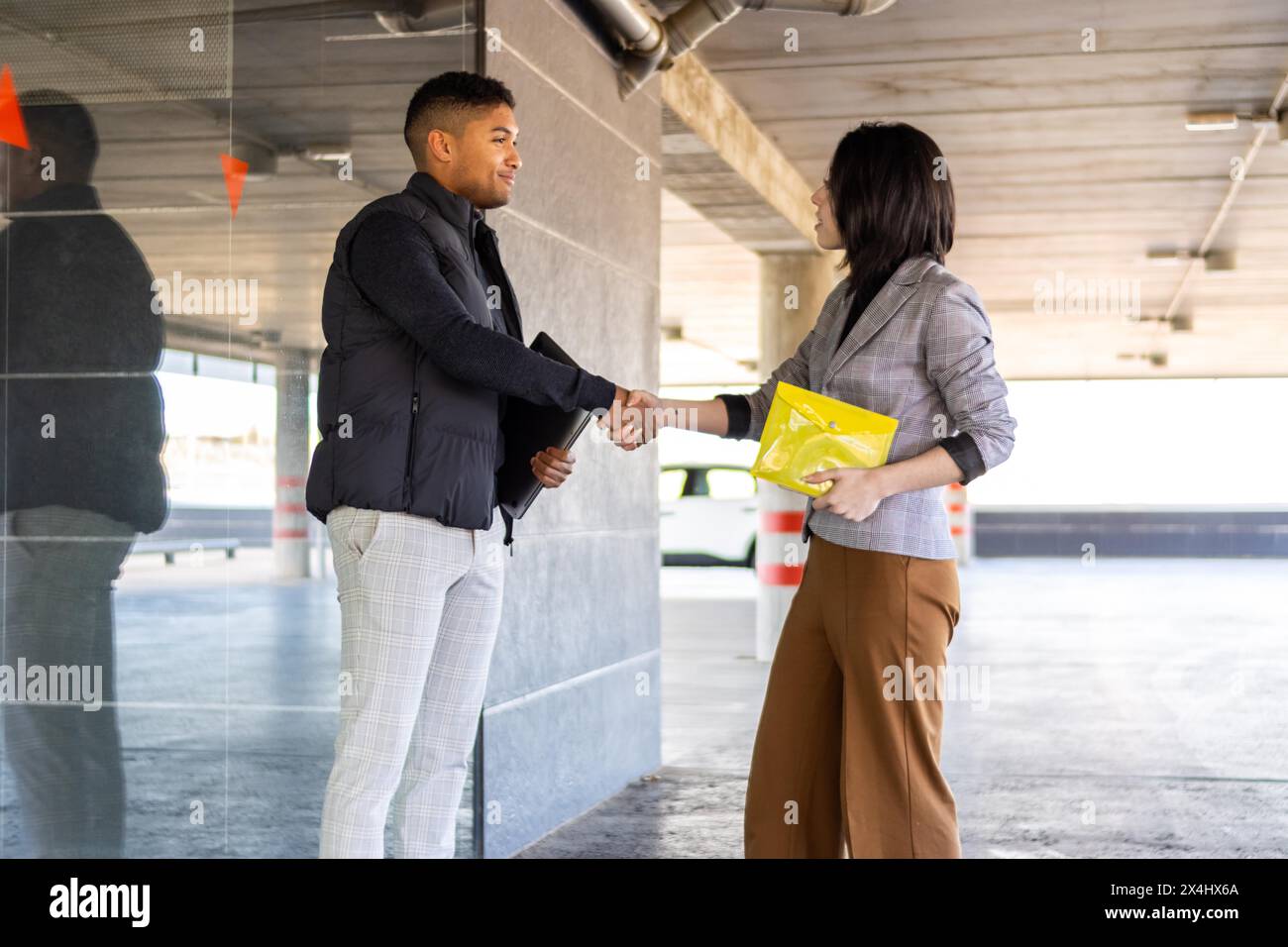Femme en costume formel serrant la main avec homme occasionnel à l'extérieur. Femme d'affaires serrant la main d'un gars dans la rue Banque D'Images