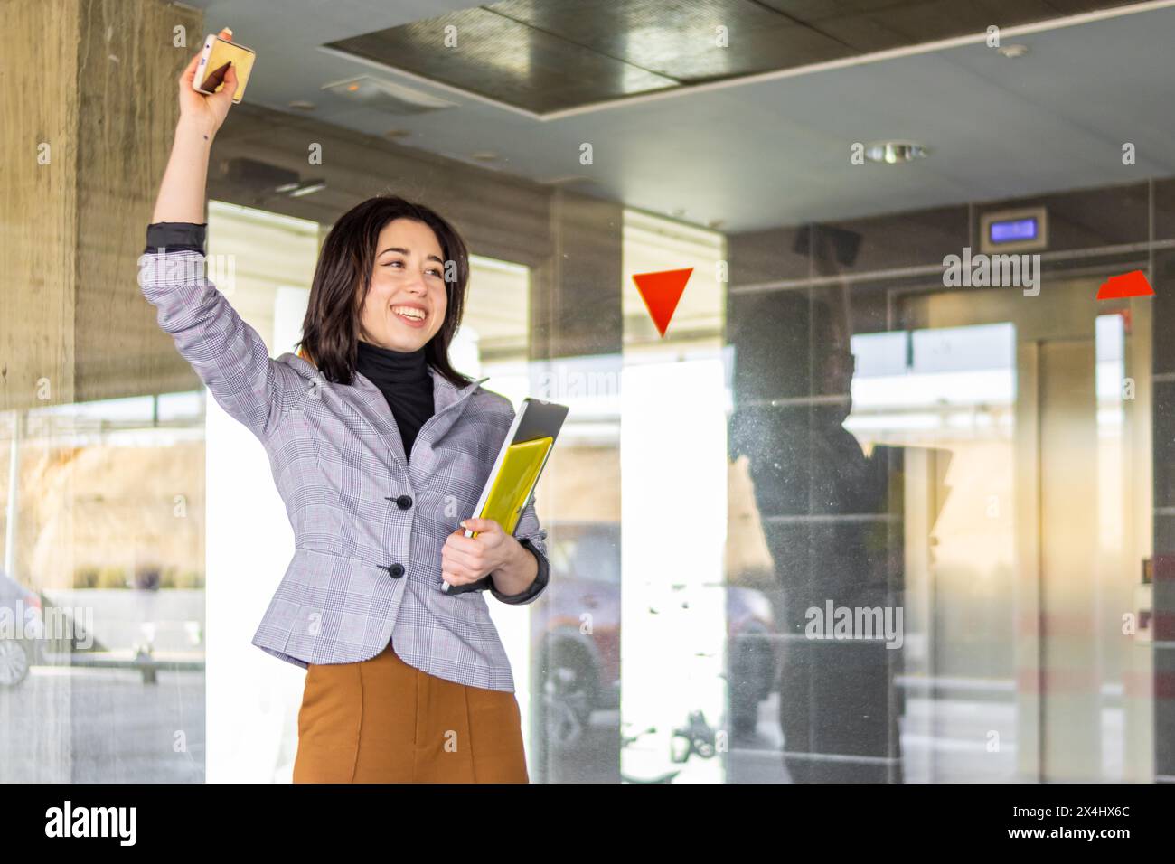 Femme en costume formel disant au revoir à une personne à l'extérieur. Portrait d'une fille d'affaires souriante faisant signe au revoir à une personne au loin Banque D'Images