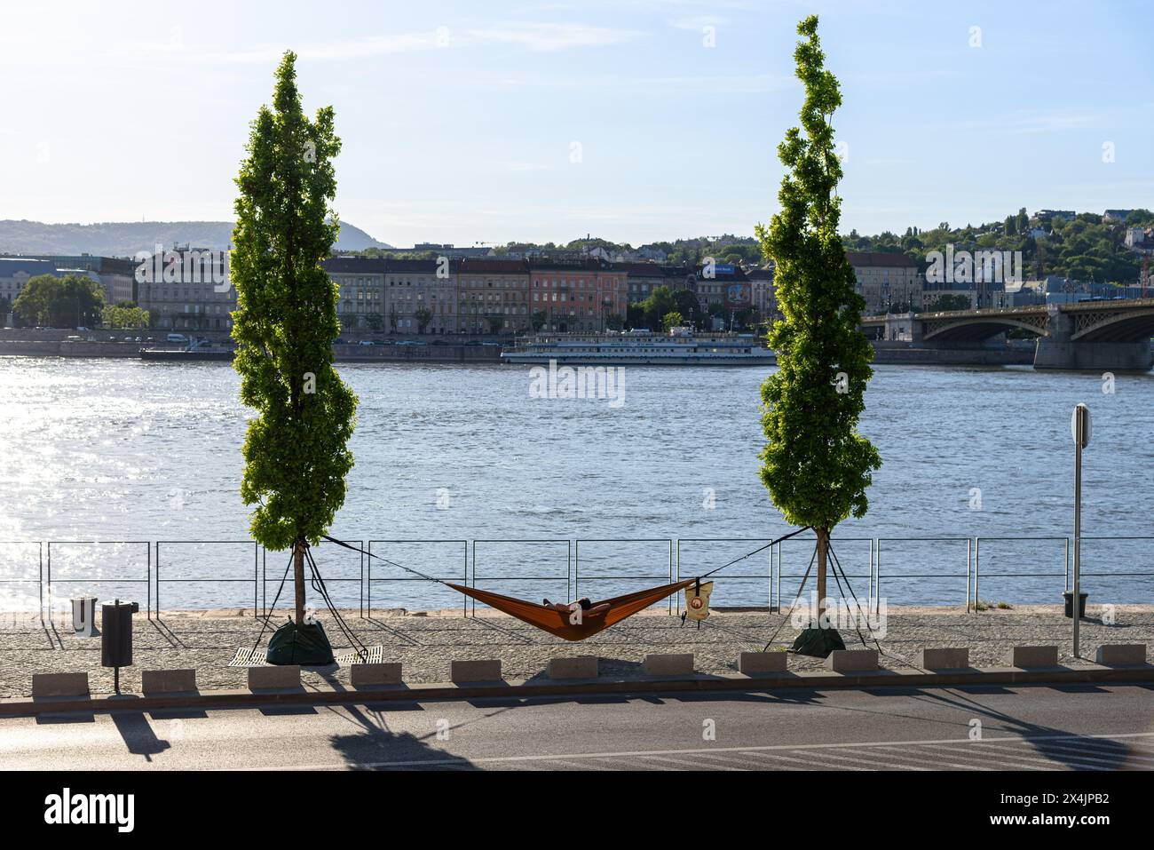 Un homme assis dans un hamac, surplombant le Danube, sur le remblai de Budapest Banque D'Images