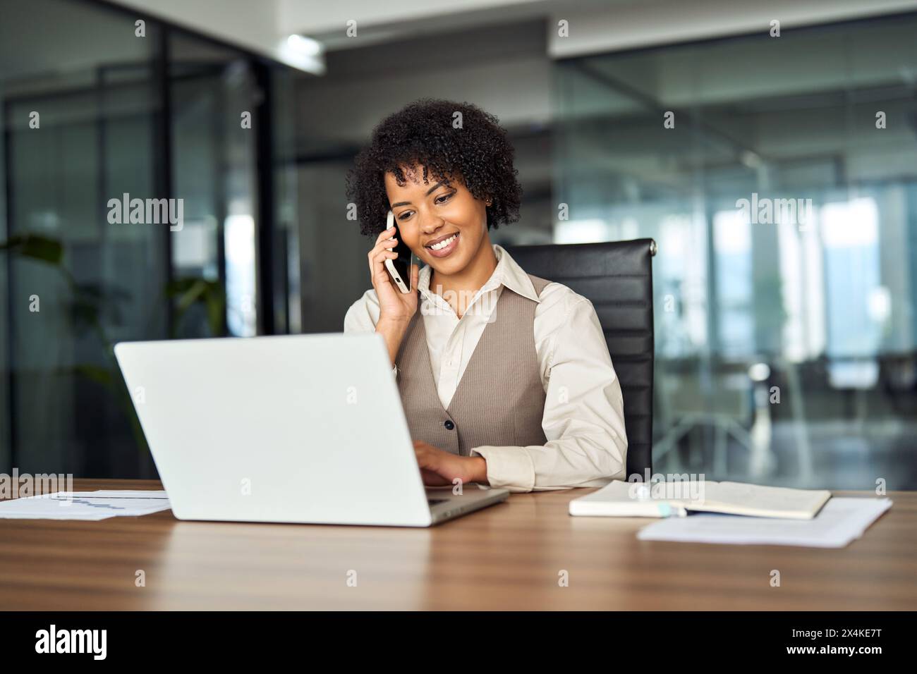 Heureuse femme d'affaires afro-américaine faisant appel parlant au téléphone au travail. Banque D'Images