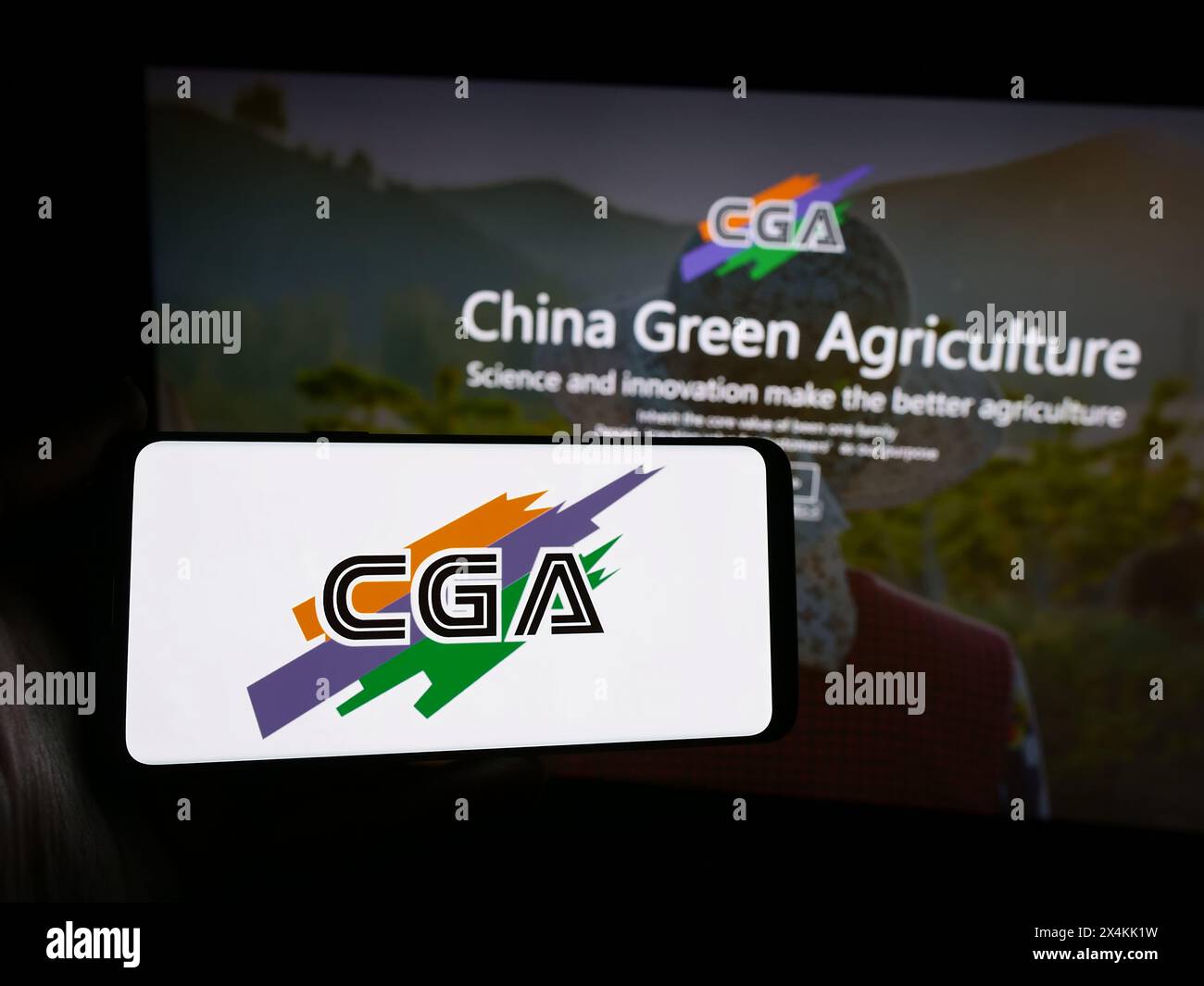 Personne tenant un smartphone avec le logo de la société chinoise China Green Agriculture Inc (CGA) en face du site Web. Concentrez-vous sur l'affichage du téléphone. Banque D'Images