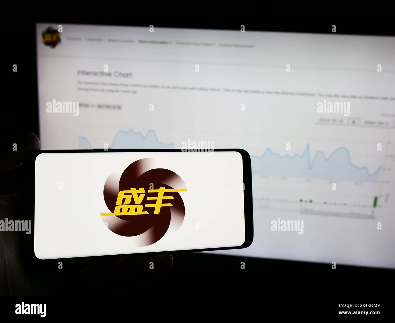 Personne tenant le téléphone portable avec le logo de la société de logistique chinoise Shengfeng Development Ltd. en face de la page Web. Concentrez-vous sur l'affichage du téléphone. Banque D'Images