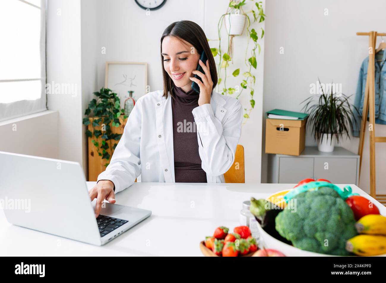 Jeune nutritionniste féminine souriante travaillant à la salle de consultation Banque D'Images