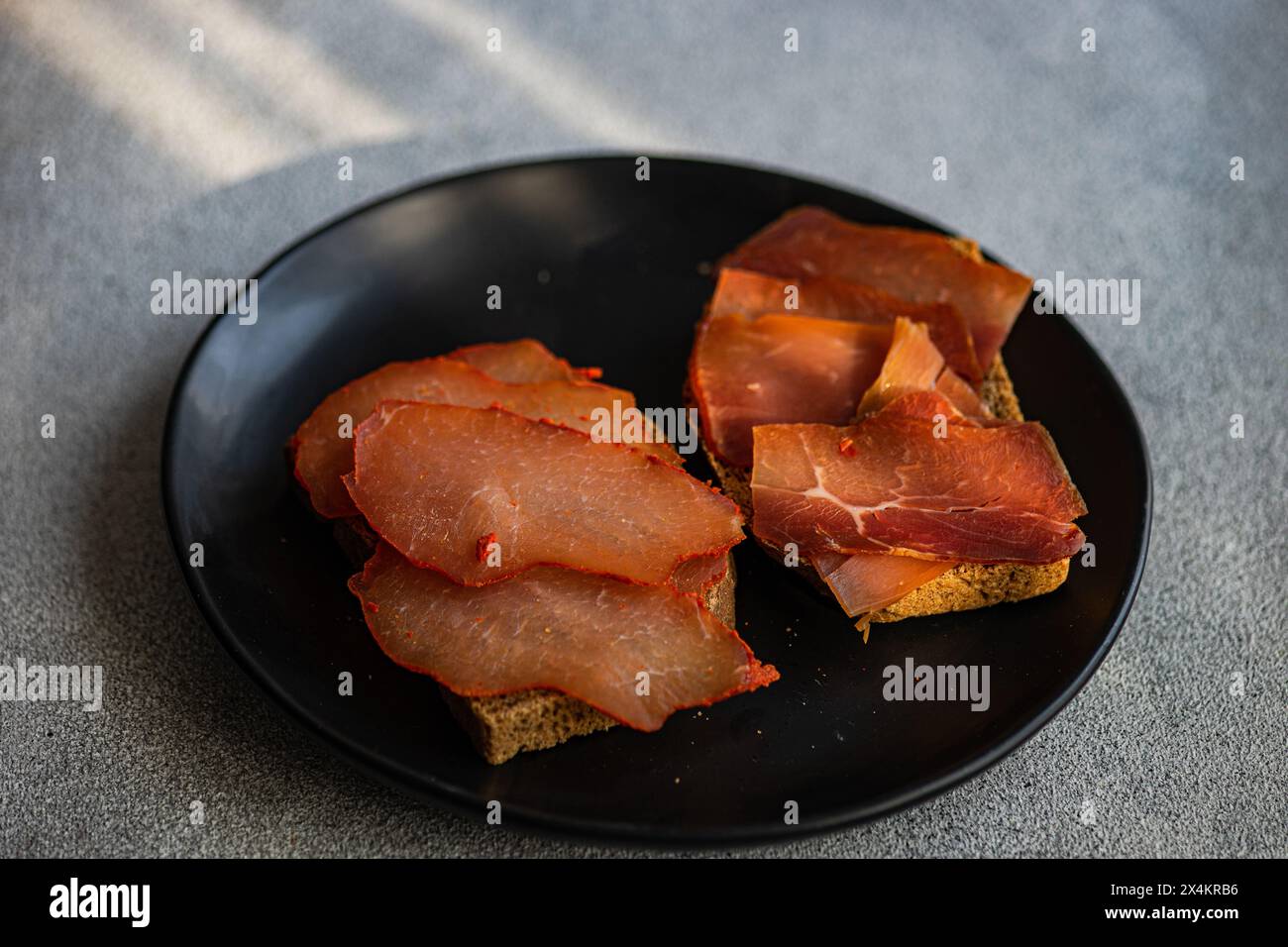 Toasts avec du pain de seigle et des tranches de viande sur l'assiette sur la table en béton Banque D'Images