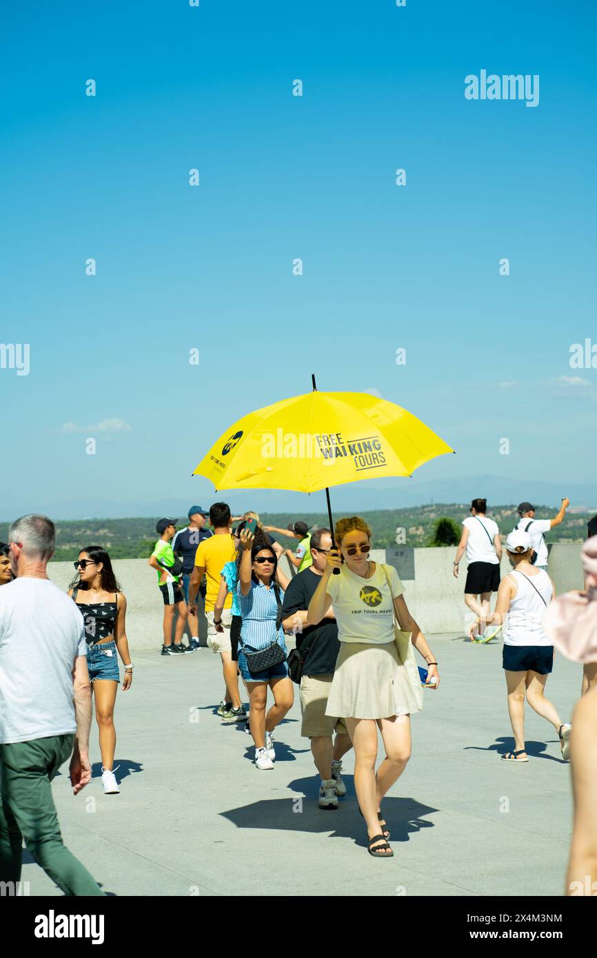 Madrid, Espagne ; 12 août 2023 : un guide avec un parapluie jaune suivi par des touristes. Concept de tourisme Banque D'Images