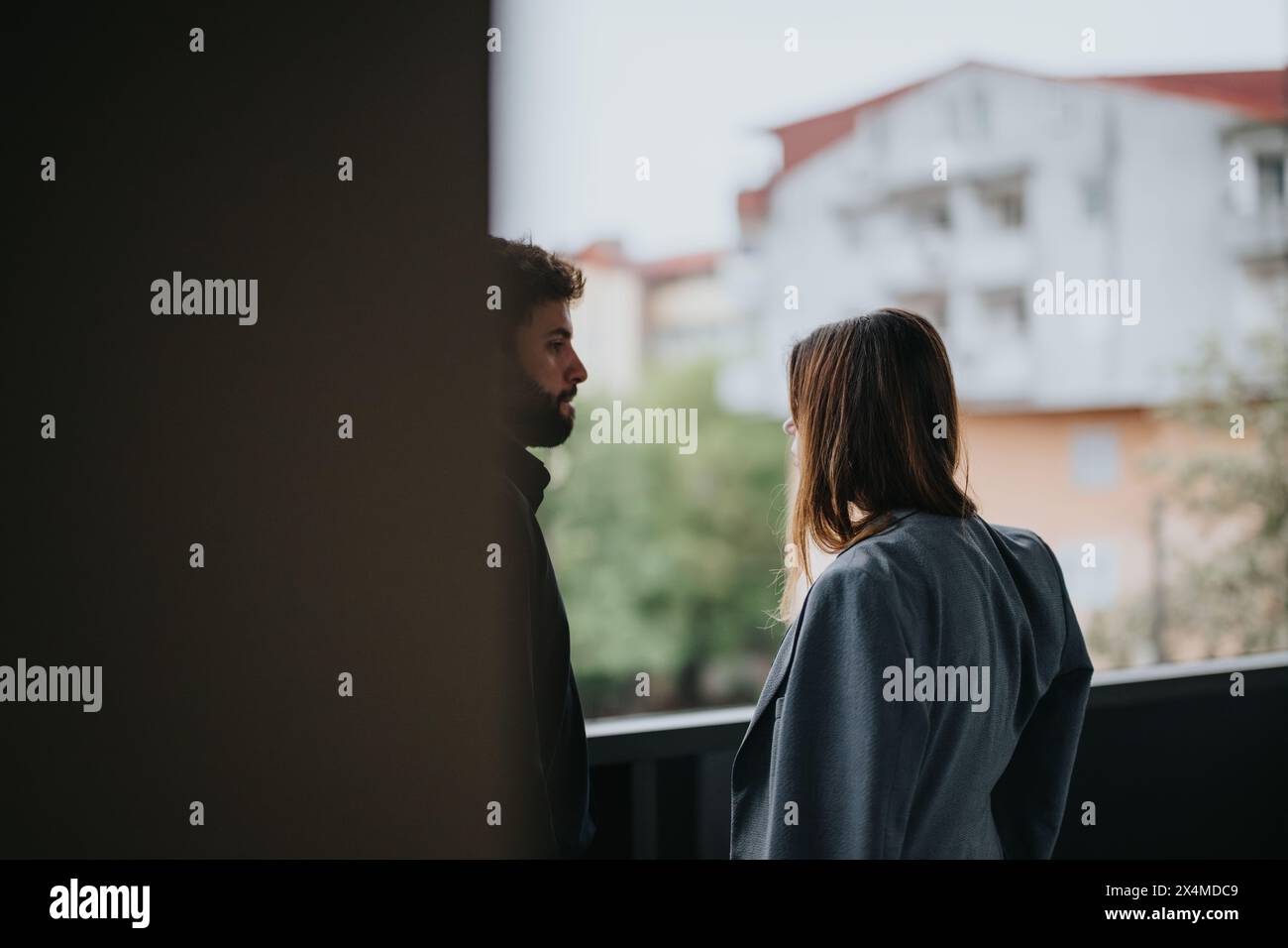 Deux jeunes professionnels ayant une conversation informelle sur un balcon surplombant la ville Banque D'Images