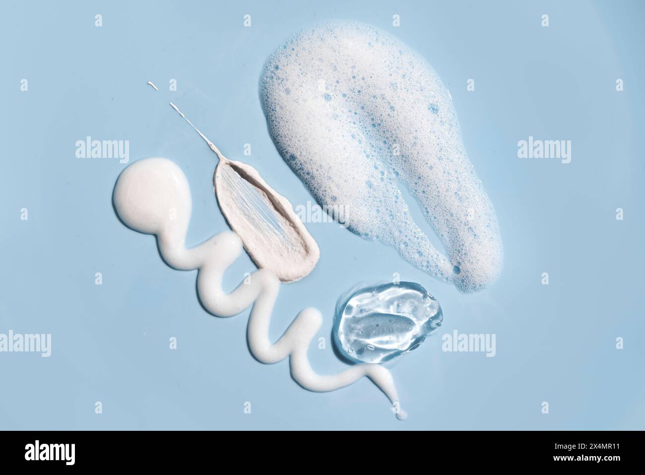 Divers nettoyants pour le visage, produits cosmétiques de soins de la peau frottent la texture des échantillons sur fond bleu. Produits démaquillants Swatch - gel lavant, mousse mousse et Banque D'Images