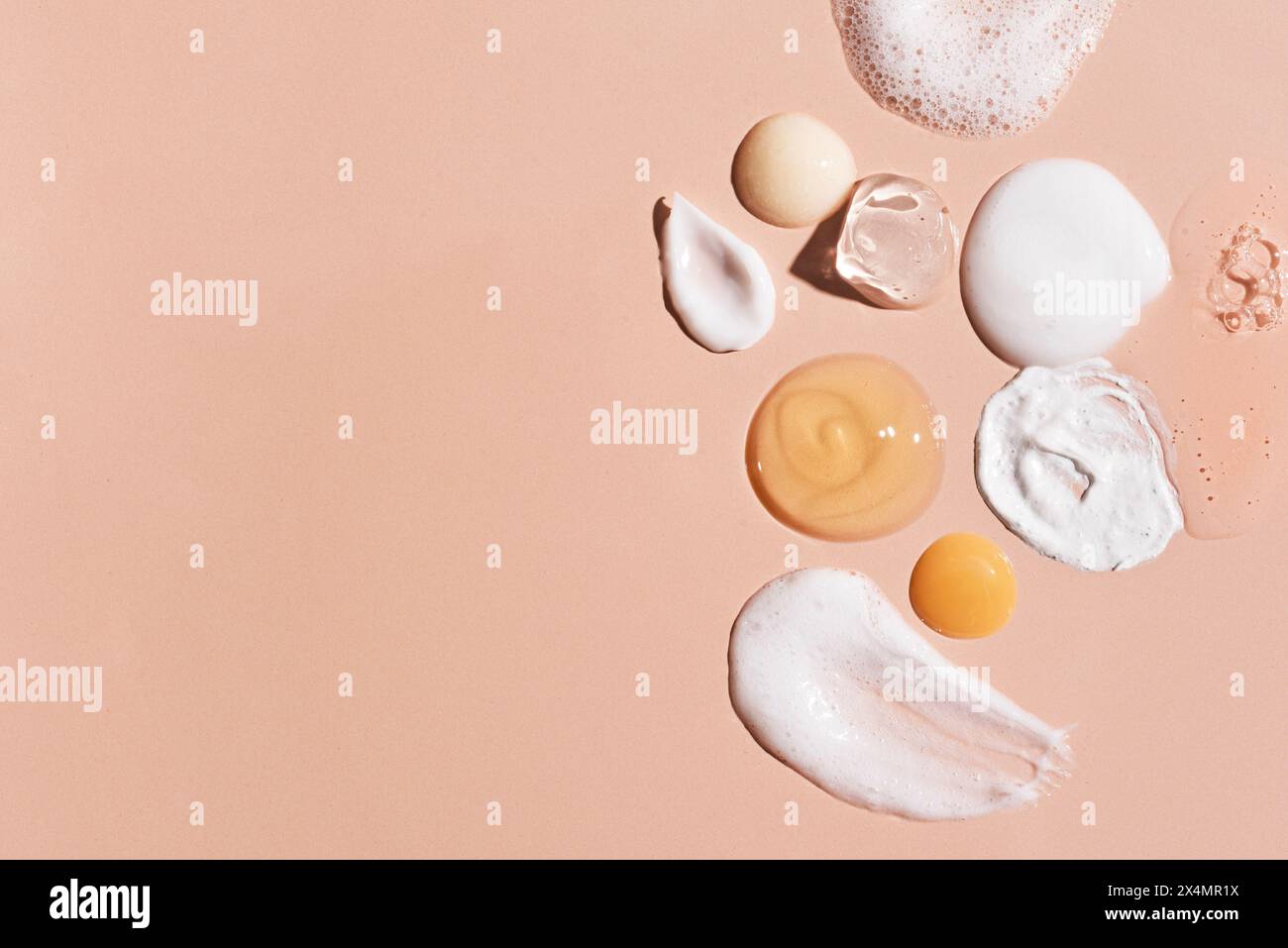 Ensemble de cosmétique échantillon sur fond rose beige, espace de copie. Produits de beauté ou de soins de la peau : hydratant, essence de sérum, mousse nettoyante, tonique, Banque D'Images