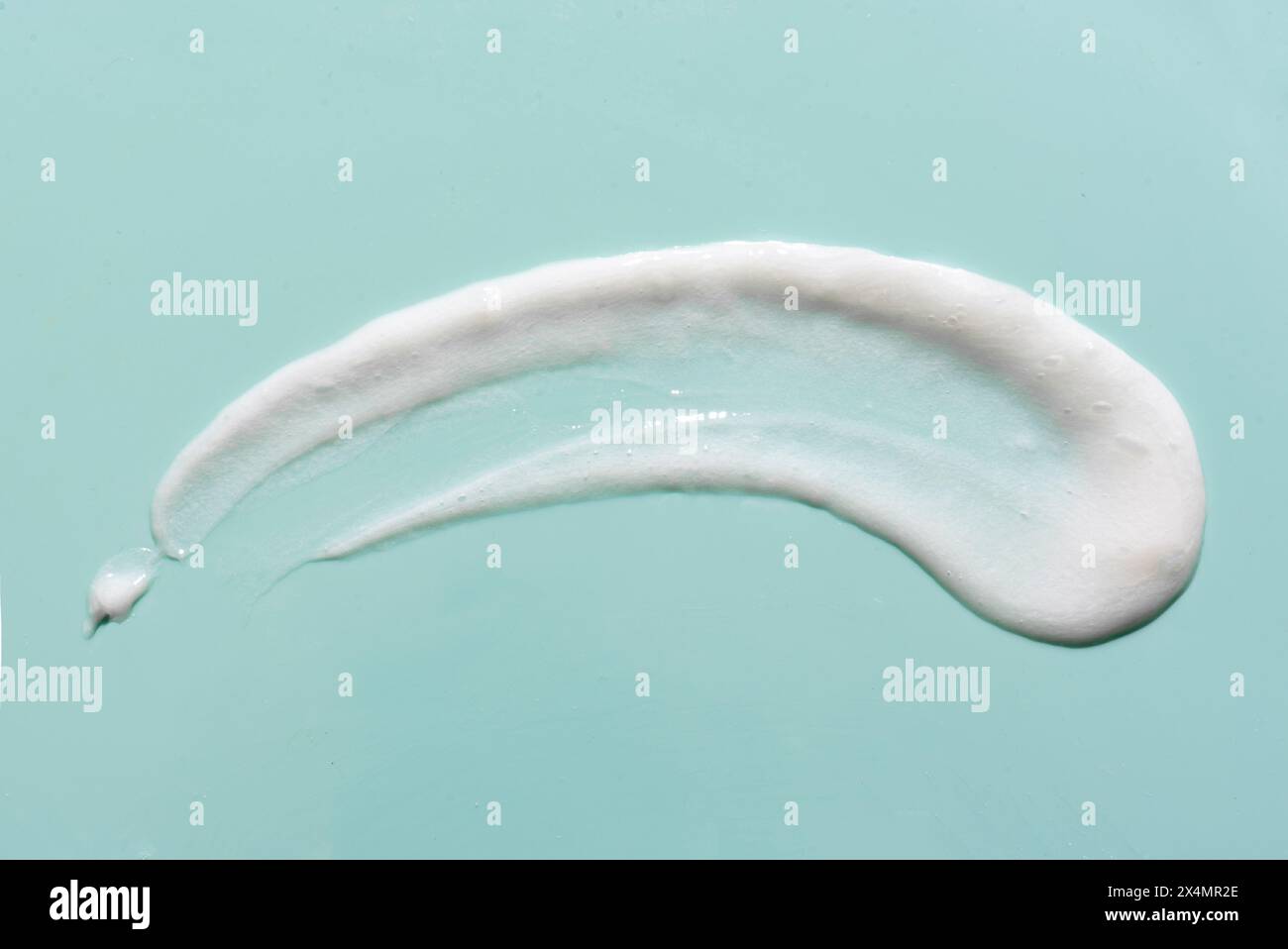 Échantillon de mousse nettoyante pour le visage. Bulles de mousse nettoyante blanche sur fond turquoise. Savon, gel douche, crème hydratante texture gros plan. Banque D'Images