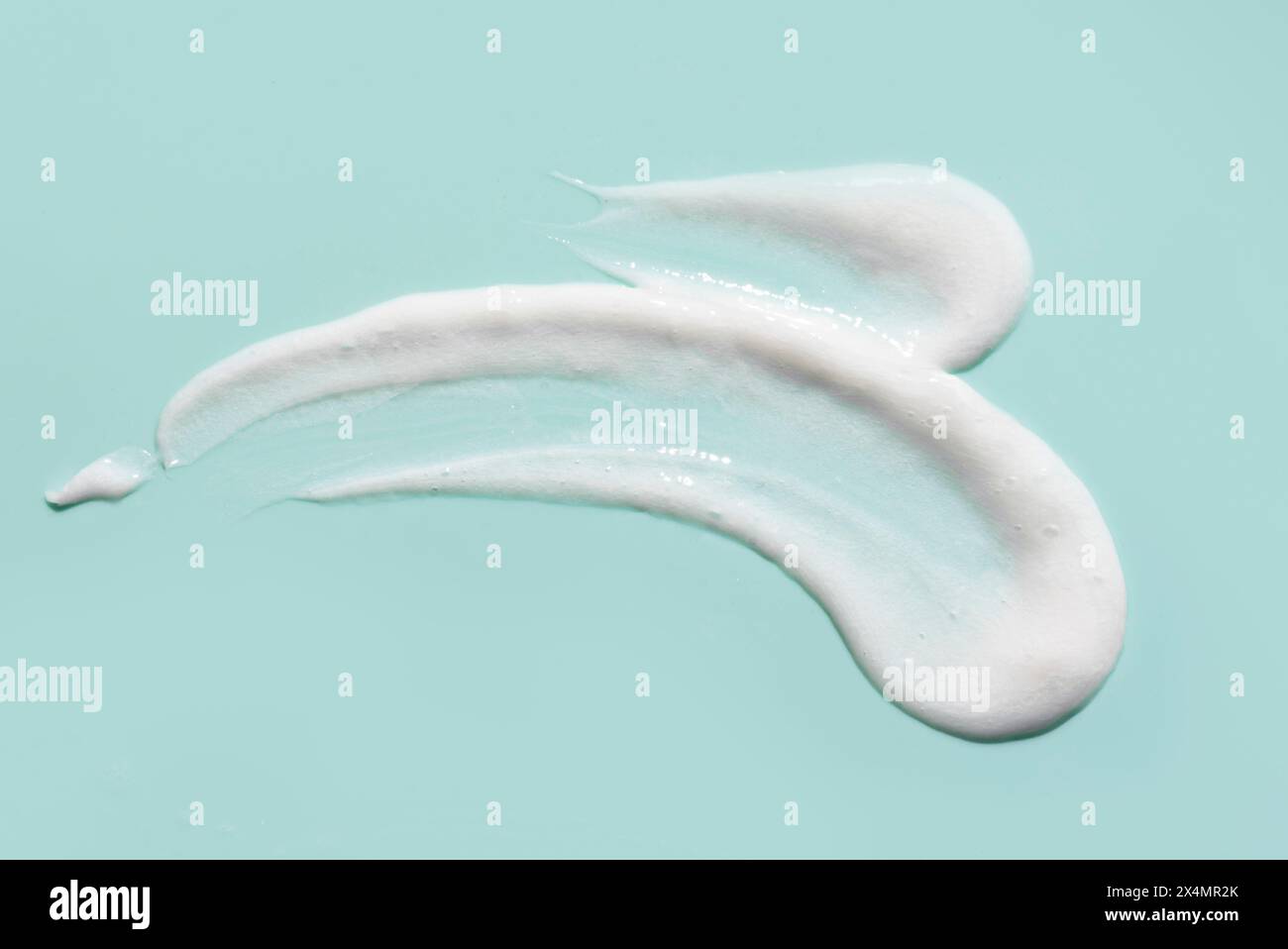 Cosmétique visage nettoyant mousse gel Smudge Drops texture sur fond bleu. Frottez un échantillon de gel de lavage blanc liquide ou de crème hydratante pour le visage. Banque D'Images